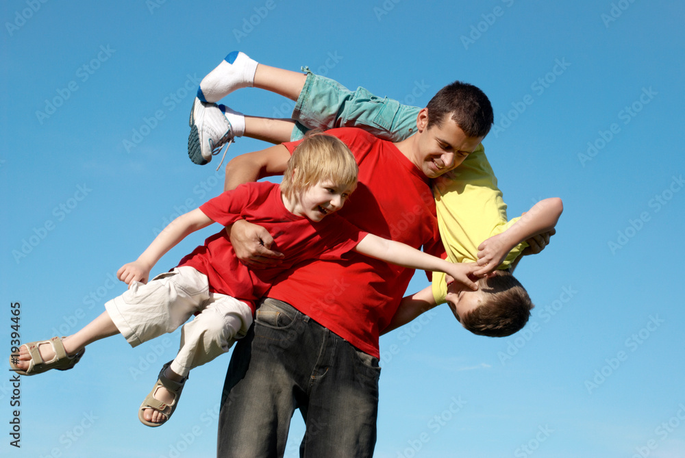 The father playing with sons against sky