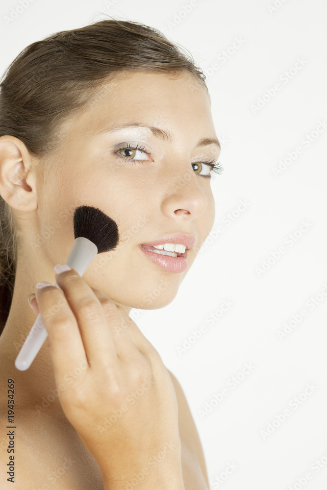 portrait of young woman putting on face powder portrait of young woman putting on face powder