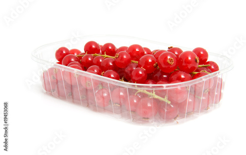 Plastic cup with red berries over white background