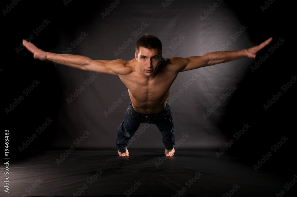 Dramatic light photo of modern acrobat in front of black backgro Dramatic light photo of modern acrobat in front of black backgro