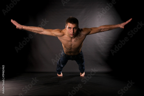 Dramatic light photo of modern acrobat in front of black backgro