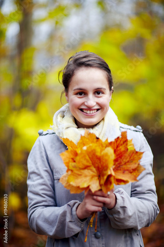 Cute young woman holding leaves in forest