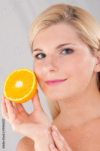 Young healthy woman with pure skin and citrus orange fruit