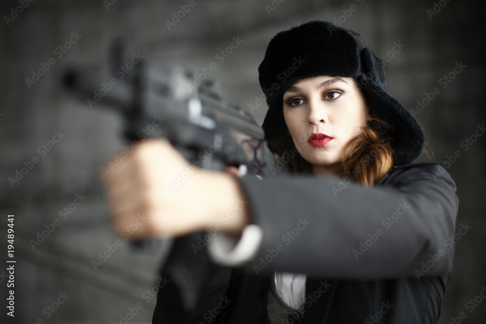 A young and stylish woman holding an assault rifle