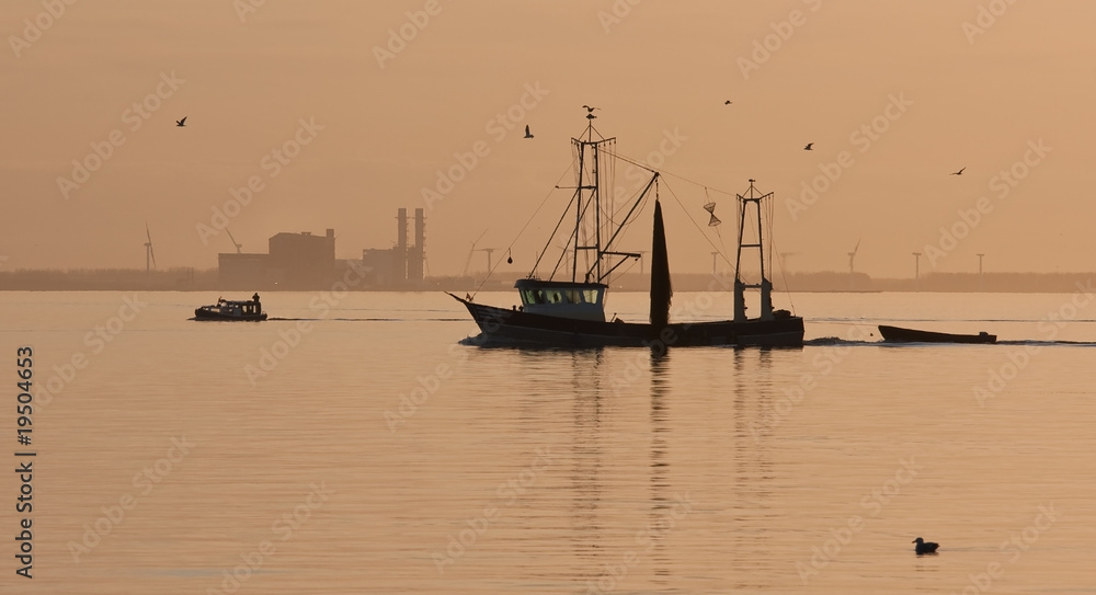 Fishing ship sailing home in sunset