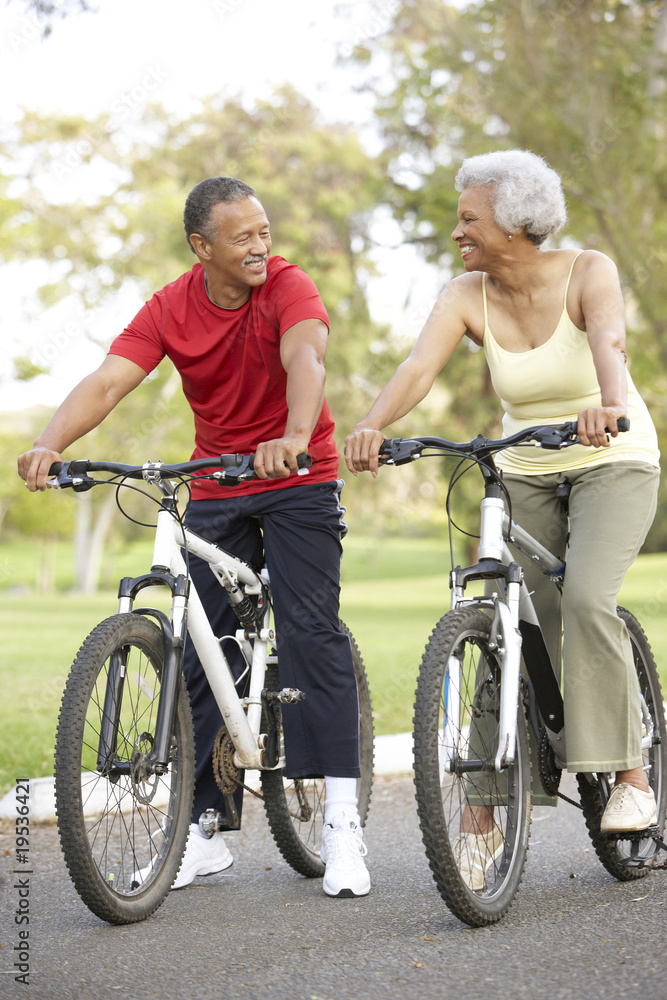 Senior Couple Riding Bikes In Park Senior Couple Riding Bikes In Park