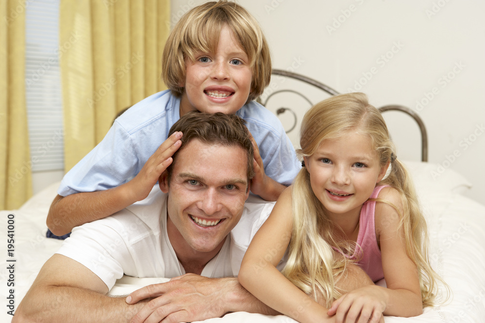 Family Relaxing On Bed At Home Family Relaxing On Bed At Home