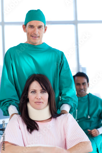 Attractive surgeon carrying a patient on a wheelchair