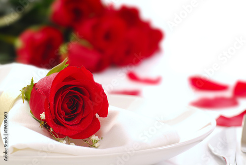 Red rose on a dinner plate with rose petals