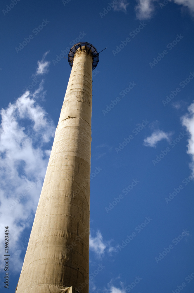 Factory chimney on the blue sky background