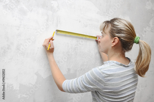 worker woman measuring on wall straightedgetape