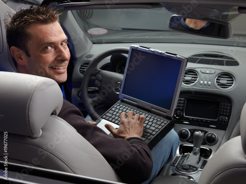 Master mechanic with his diagnostic computer sitting in open car