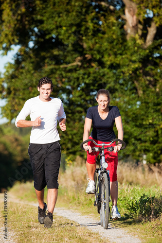 Young sport couple jogging and cycling © Kzenon