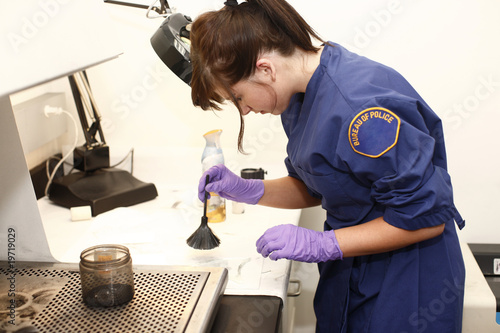 female criminologist dusting an item for fingerprints photo