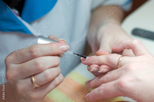 Manicurist applying clear polish on customer