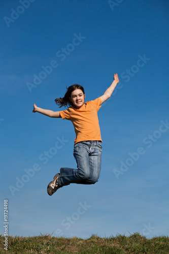 Girl running, jumping against blue sky