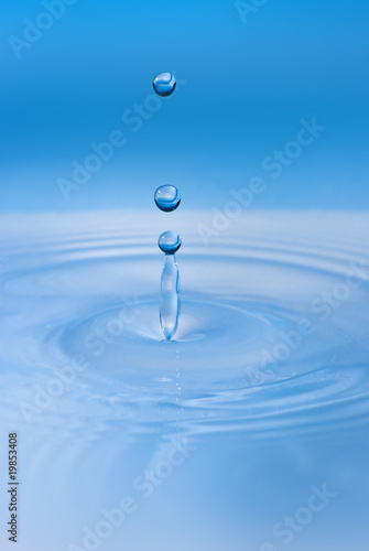 Clean blue drop of water splashing in clear water. Abstract blue