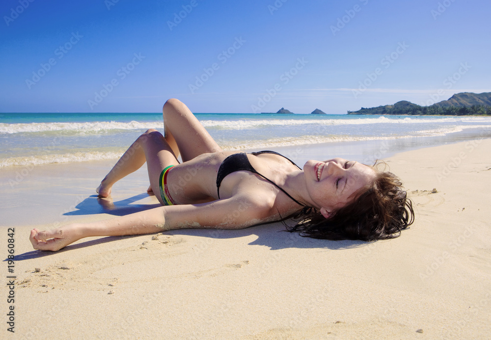 young woman in a bikini lounging on the beach in hawaii Stock Photo