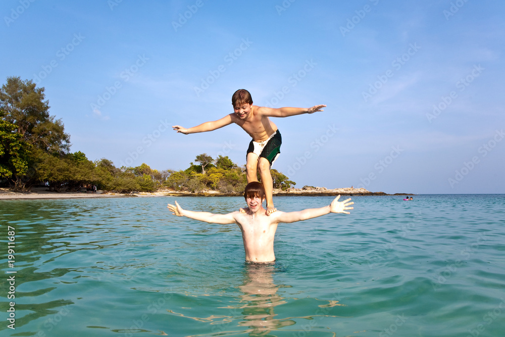 brothers are playing together pickaback  in a beautiful sea