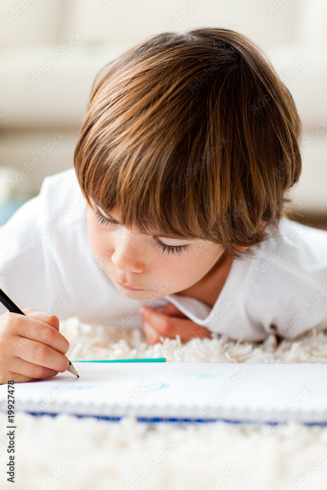 Serious little boy drawing lying on the floor Serious little boy drawing lying on the floor
