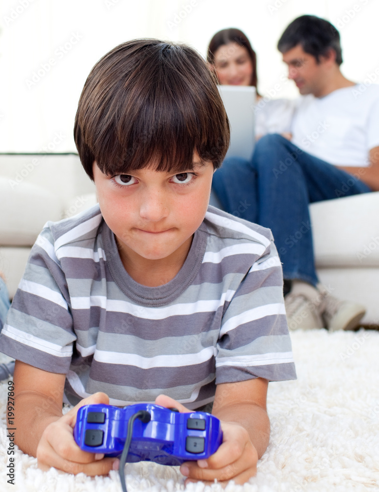 Concentrated boy playing video games lying on the floor Concentrated boy playing video games lying on the floor