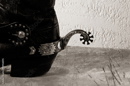 Obraz na plátně Cowboy boots with spurs on the wooden desk