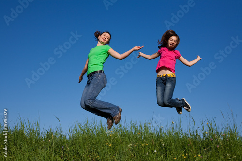Mother and daughter  jumping  running against blue sky
