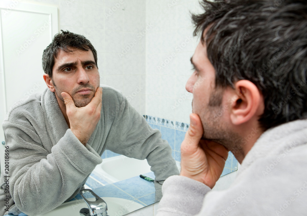 Homme qui se regarde dans le miroir Photos Adobe Stock