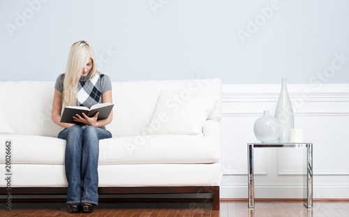 Woman Sitting on Couch and Reading Book