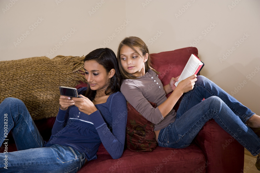 Sisters relaxing together at home on sofa Sisters relaxing together at home on sofa