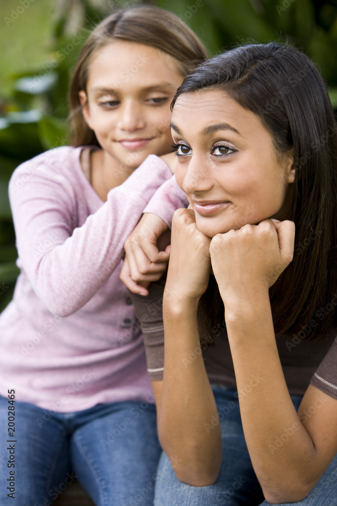 Close-up of pretty teenage girl and younger sister smiling Close-up of pretty teenage girl and younger sister smiling
