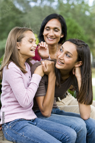 Affectionate mother and two daughters laughing together