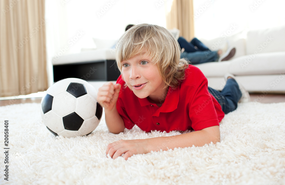 Excited boy watching football match lying on the floor