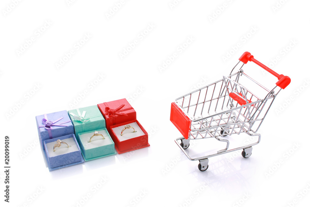 Three rings in gift boxes with empty shopping cart isolated Three rings in gift boxes with empty shopping cart isolated