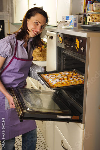 Hausfrau holt eine Kuchen aus dem Ofen