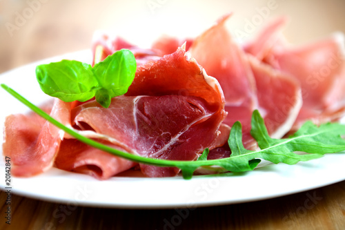 Sliced dry-cured ham with arugula and basil
