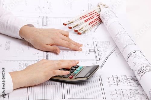 hands with house construction plan and calculator