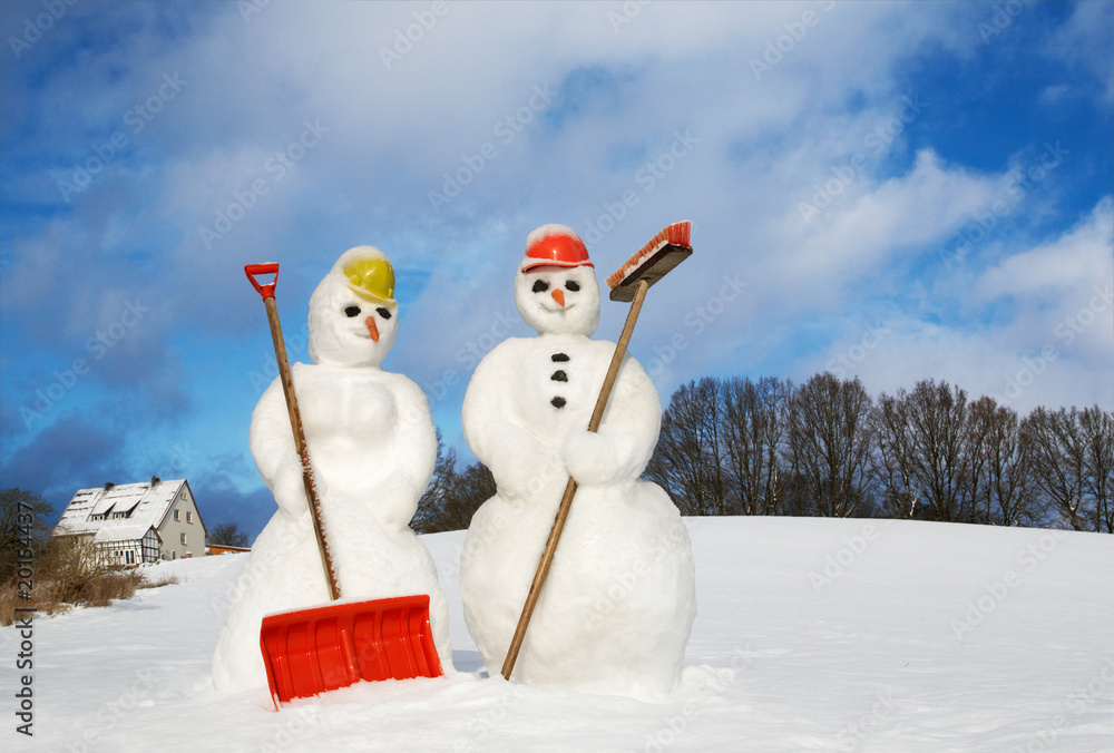 Obraz premium snowwoman and snowman with snow shovel and broom