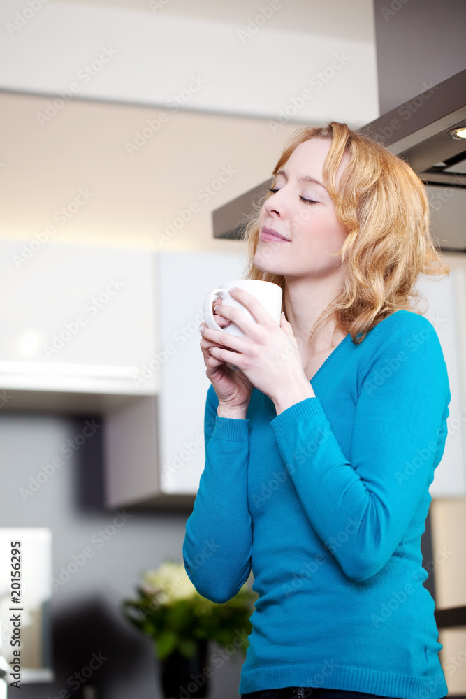 junge frau trinkt eine heiße tasse tee in der küche junge frau trinkt eine heiße tasse tee in der küche