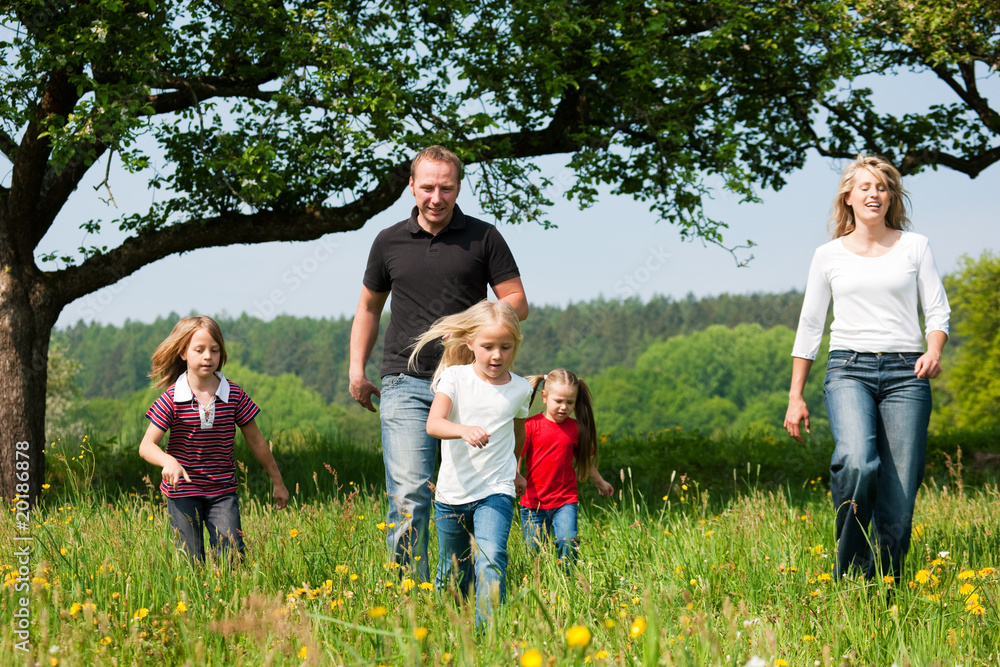 Fototapeta premium Familie rennt über eine Wiese im Frühling