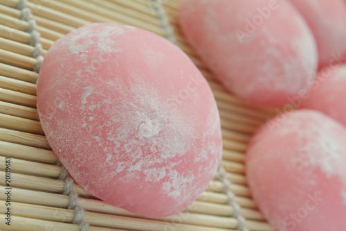 Closeup of pink japanese rice cakes on bamboo mat