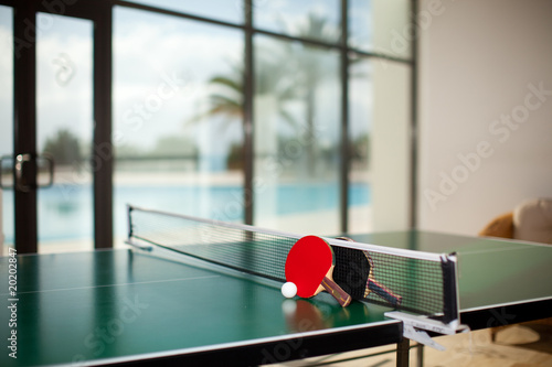 Table tennis rackets and ball, pool in the background