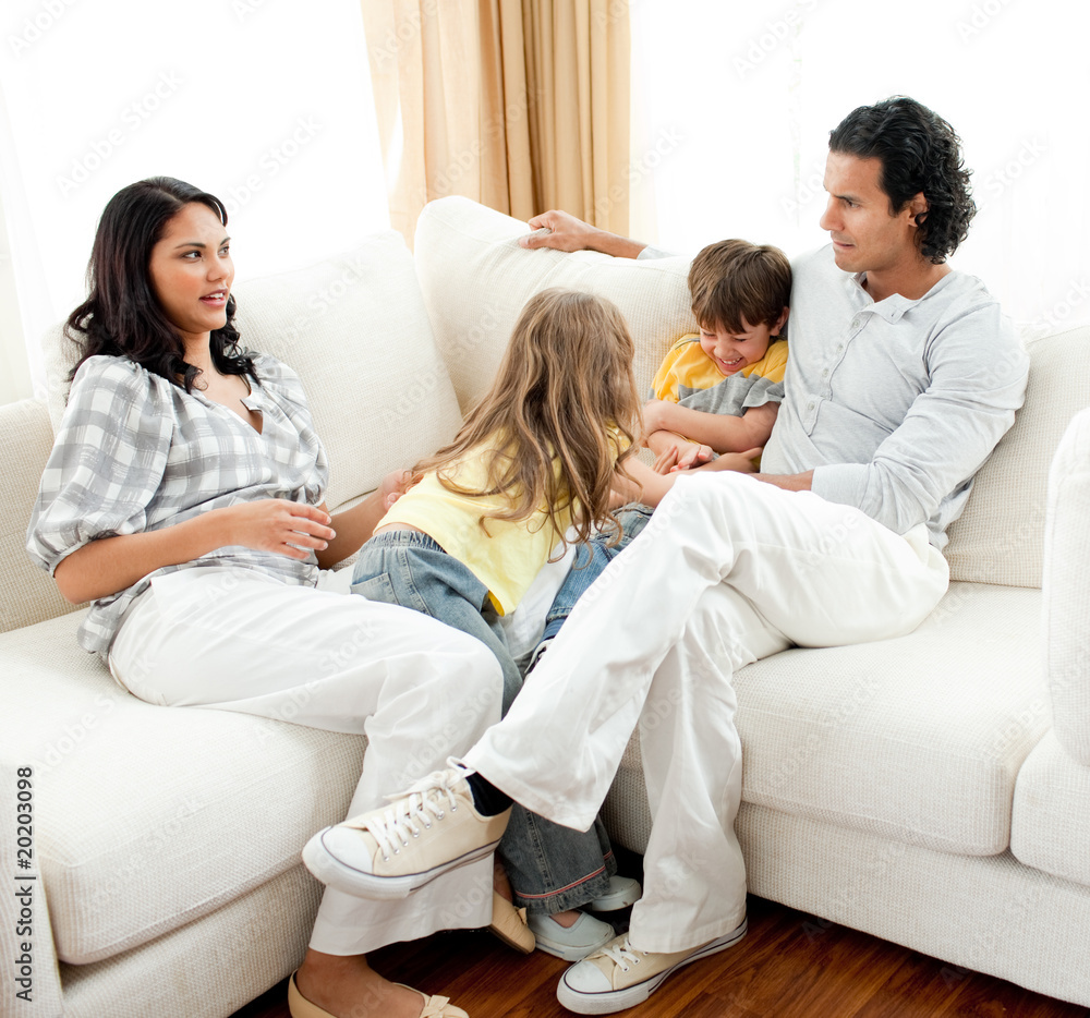 Attentive parents sitting on sofa with their children Attentive parents sitting on sofa with their children