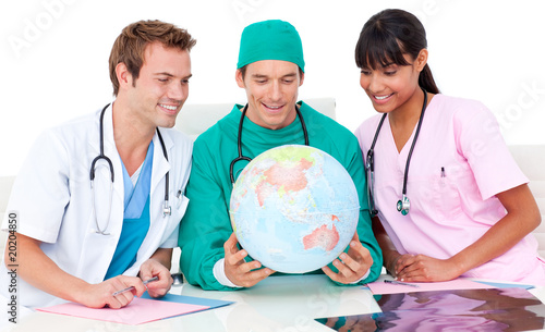 Cheerful medical team looking at terrestrial globe