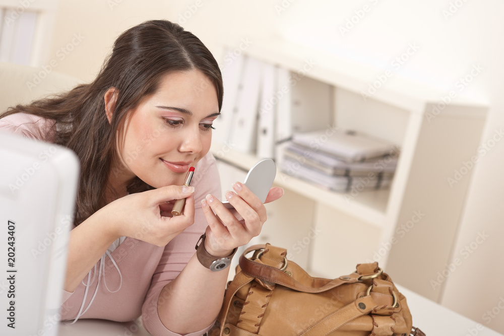 Young executive woman applying lipstick at office Young executive woman applying lipstick at office