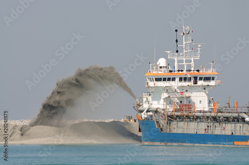 Dredge ship pipe pushing sand to create new land photo