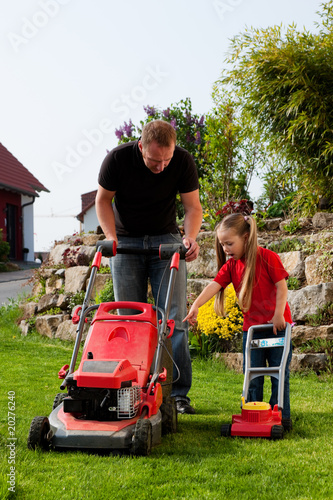 Obraz na plátně Vater und Kind mähen zusammen den Rasen