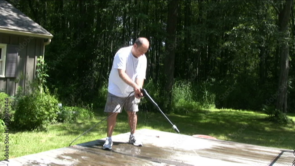 man power washing deck at suburban home