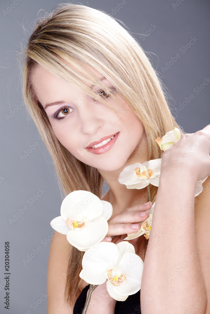 Junge blonde Frau mit Orchidee lächelnd Porträt