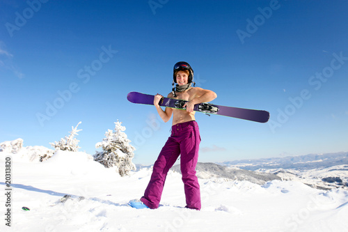Female skier topless with a ski standing on the heel